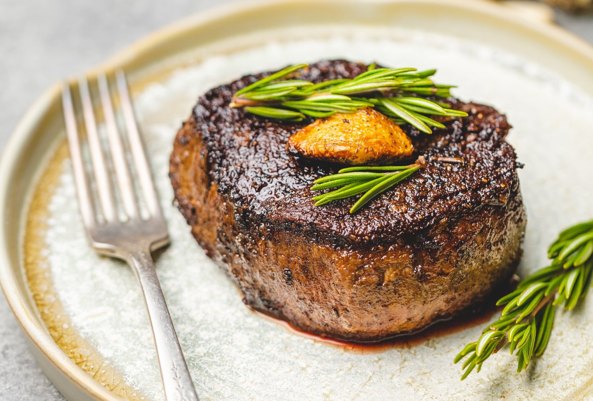 Grilled round steak seasoned with rosemary leaves.